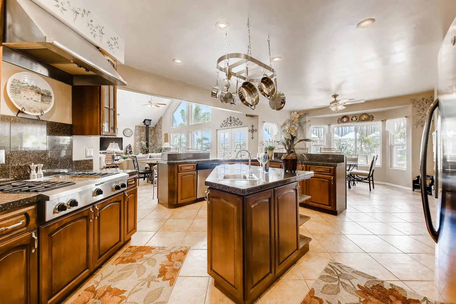 The chef's kitchen with a granite island, a four-burner commercial gas range and a hanging pot rack