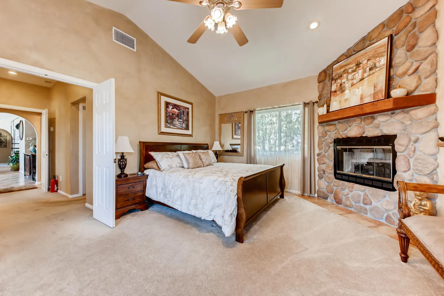 The Executive Suite with a king bed and a river-rock fireplace under a vaulted ceiling