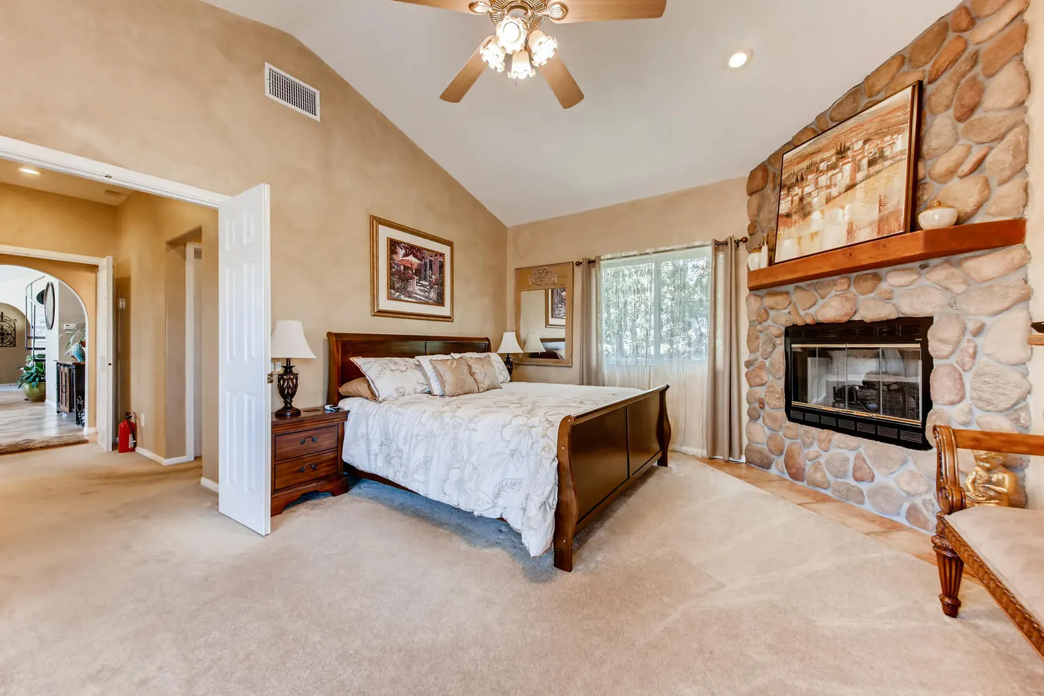 The Executive Suite with a king bed and a river-rock fireplace under a vaulted ceiling