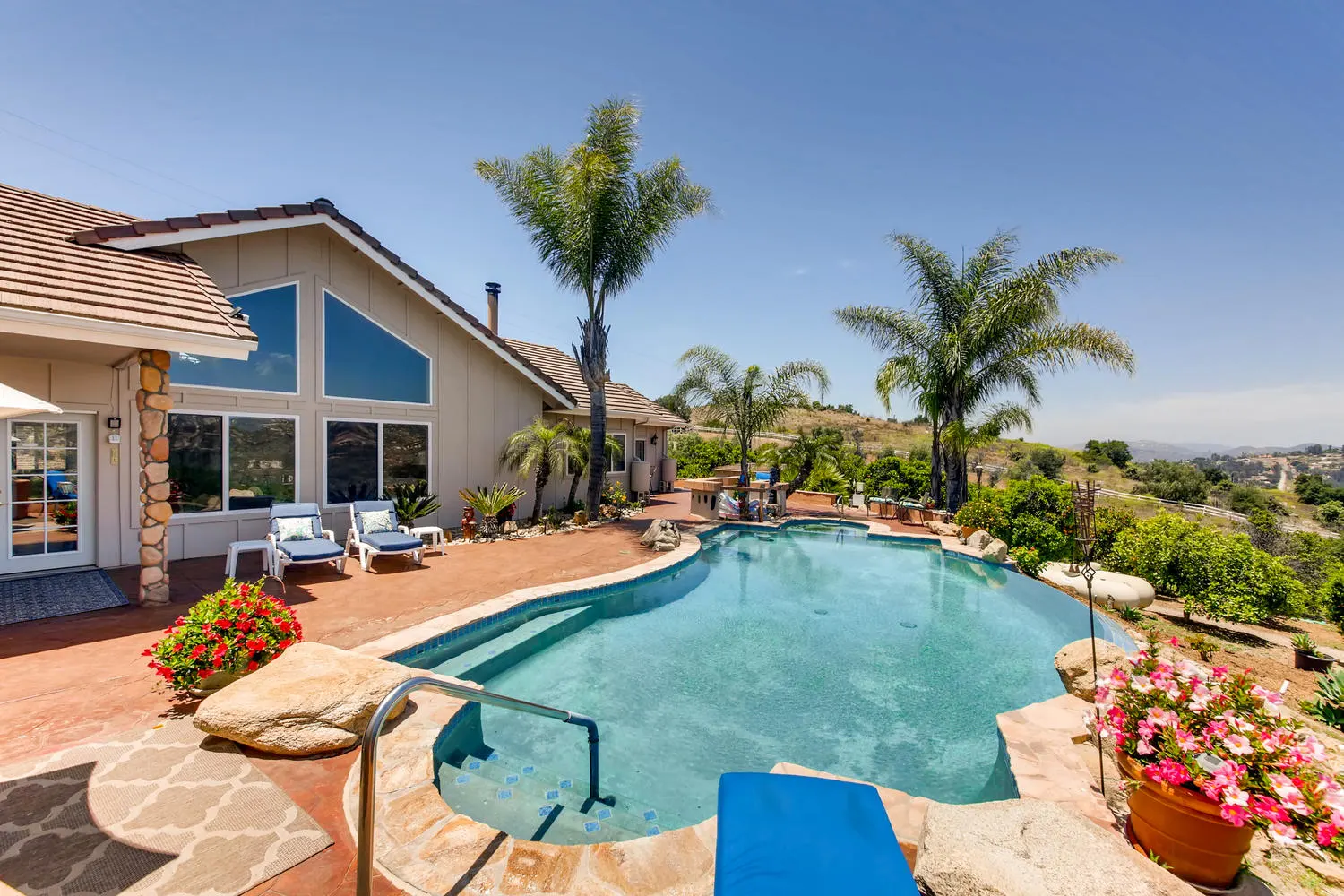 The heated saltwater pool with the main house, palms and the valley beyond